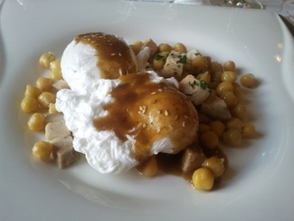 Huevos escalfados con garbanzos y tocino fresco.