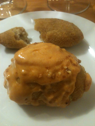 Alcachofa rellena con salsa de almendra y croqueta al fondo