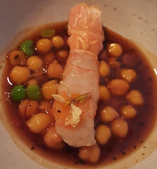 Cigala en su propua mantequilla, caldo de manitas, garbanzos y habitas tiernas.