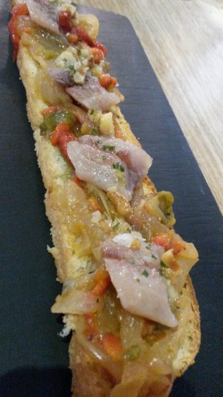 Coca de sardinas sobre escalibada y avellanas