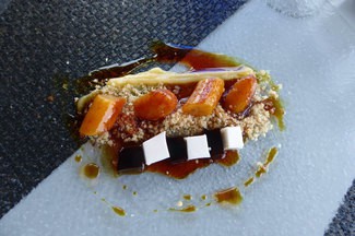 Platano estofado al caramelo oscuro, sobre tierra de galleta maria, crema de limon y gelatina de coco-café