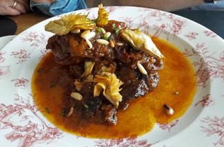 Pintada de payés asada a la catalana con ciruelas, piñones, orellanas y alcachofas