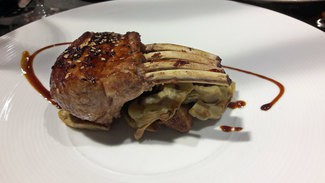 Carré de cordero lechal glaseado con miel, espárragos y alcachofas.