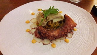 Rejo de pulpo asado, ravioli de calamar con arroz meloso de lapas y crujiente de arroz negro sobre carpaccio de pulpo