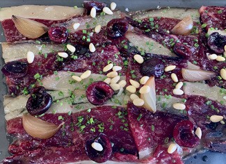 Lascas de vacuno curado con cebolla encurtida, piñones y cerezas