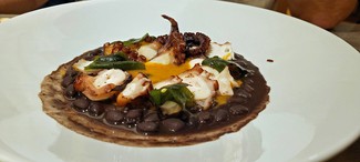 Pulpo sobre mojo hervido de chile dulce y judias negras.