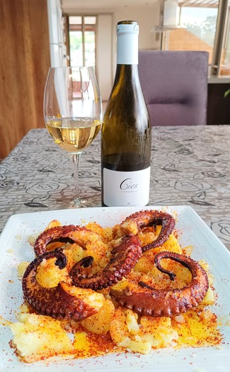 Con unas patitas de pulpo a la plancha sobre un lecho de patatas con pimentón.