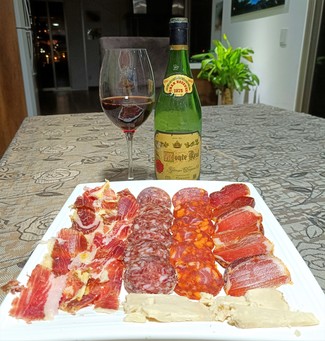 Con el surtido de queso curado de oveja, embutidos y jamón ibéricos.