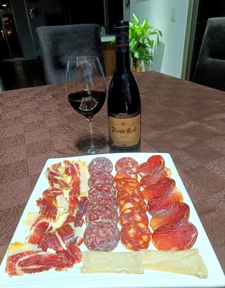 Con un surtido de queso curado de oveja, embutidos y jamón ibéricos