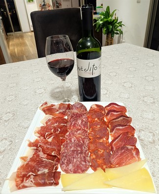Con un surtido de queso curado de oveja, embutidos y jamón ibéricos