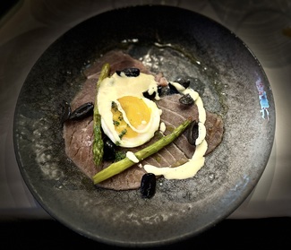 Carpaccio de chuletón de atún rojo, huevo poché, espárragos trigueros y refrito de ajos y aceitunas negras.
