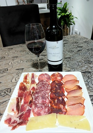 Con un surtido de queso curado de oveja al romero, embutidos y jamón ibéricos.