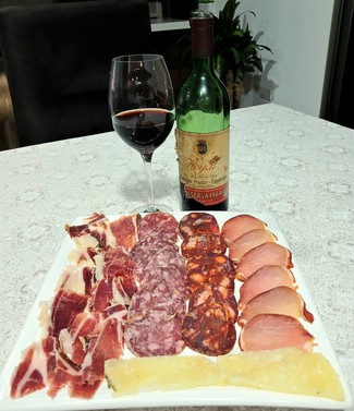 Con un surtido de queso curado de oveja al romero, embutidos y jamón ibéricos.