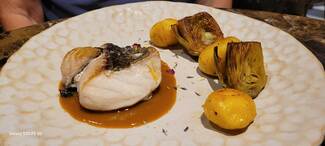 cherne, con crema de marisco, alcachofas y papas negras.