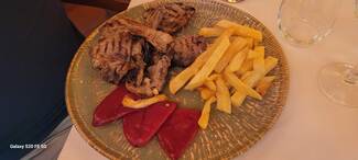 Costillas de cordero del valle a la parrilla con piquillos confitados y patatas fritas.
